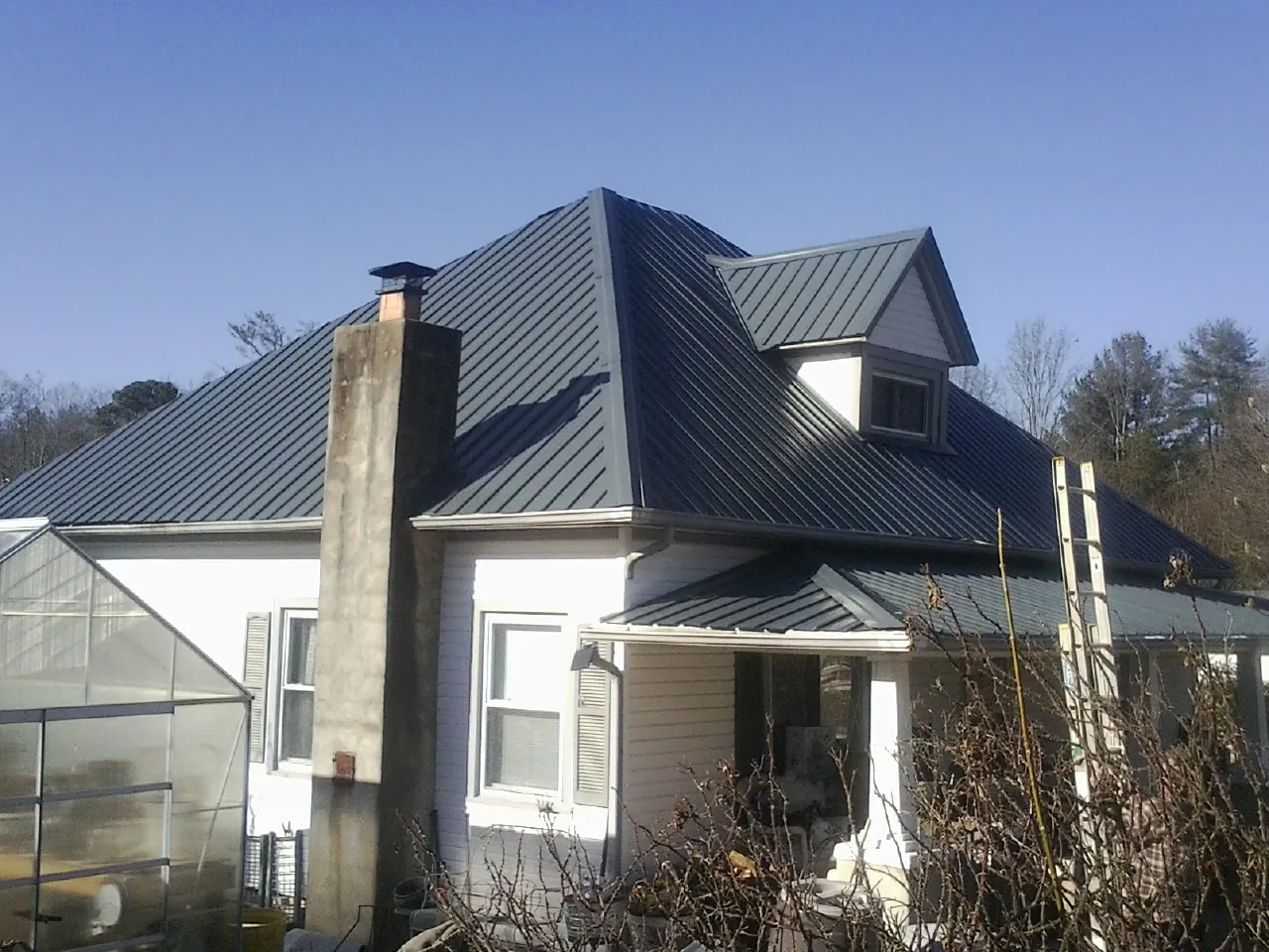 Dark blue standing seam metal roof on a white farmhouse with dormer — Slate & Tile Roof Repair by Roofing Brothers in Turkey