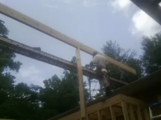 Carpenter setting a ridge beam over a new addition frame — Ice Dam Removal by Roofing Brothers in Turkey