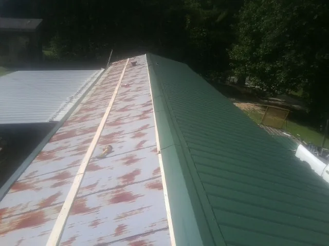 Old rusted panels beside newly installed green metal roofing — Wind Damage Roof Repair by Roofing Brothers in Turkey