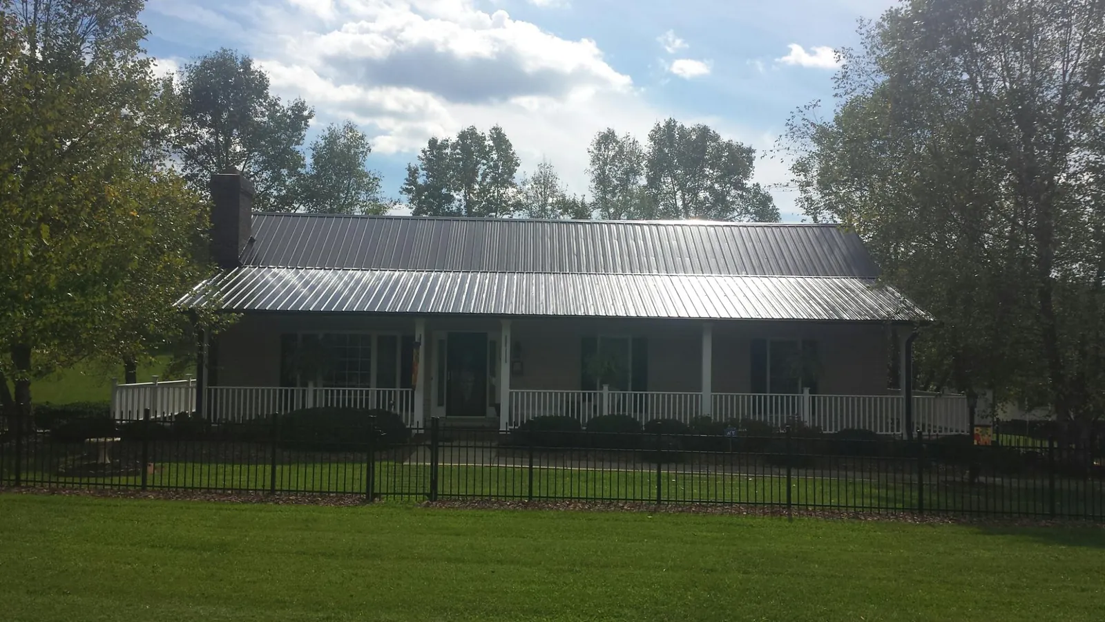 Gray metal roof on a brick ranch with a full width front porch — Gutter Guard Installation work by our crew in Turkey