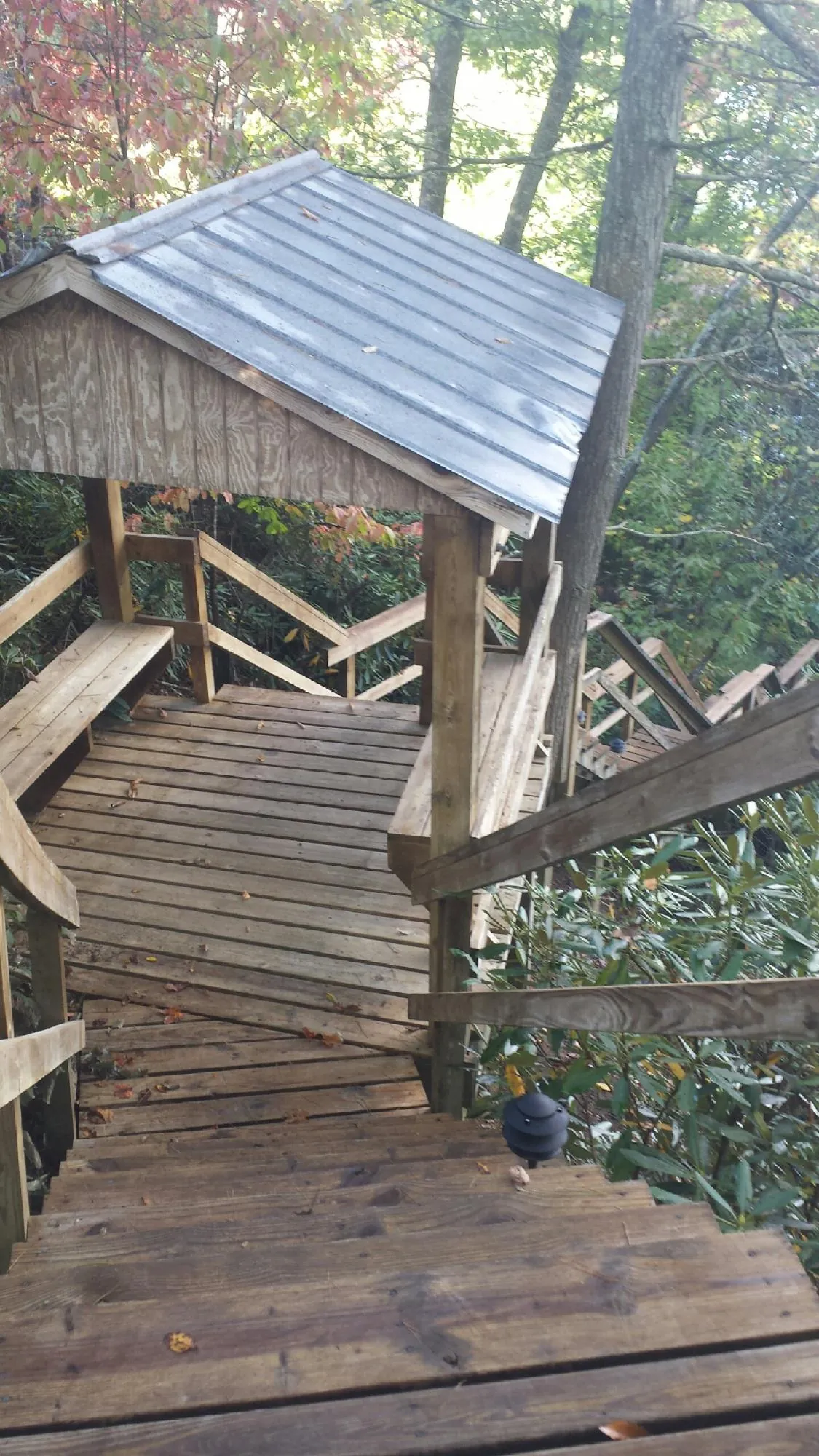 Metal roofed shelter over wooden steps on a wooded walkway — Skylight Repair & Installation work by our crew in Turkey