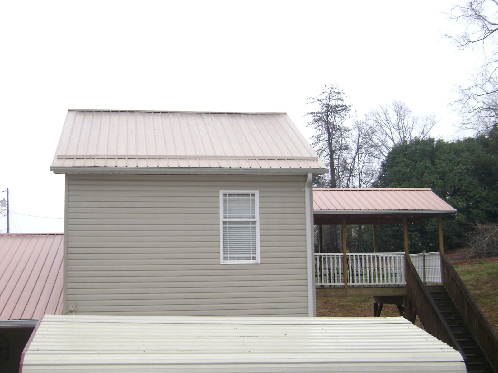 Tan metal roofs on a two story addition and attached porch, from a Roof Replacement job in Turkey