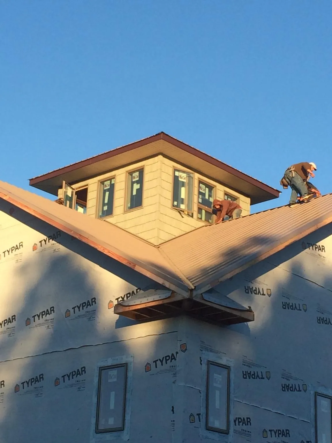 Roofers working around a rooftop cupola on a new metal roof at sunset — Roof Waterproofing in Turkey by Roofing Brothers